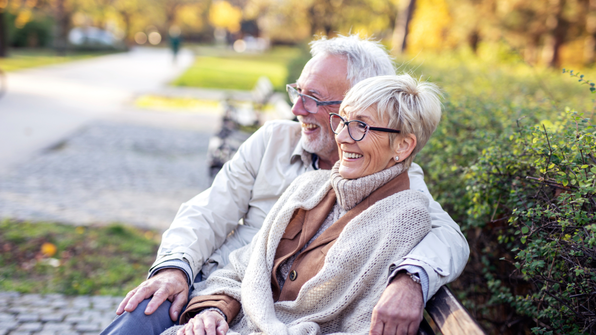 retired couple enjoying a fall day in the park on a bench